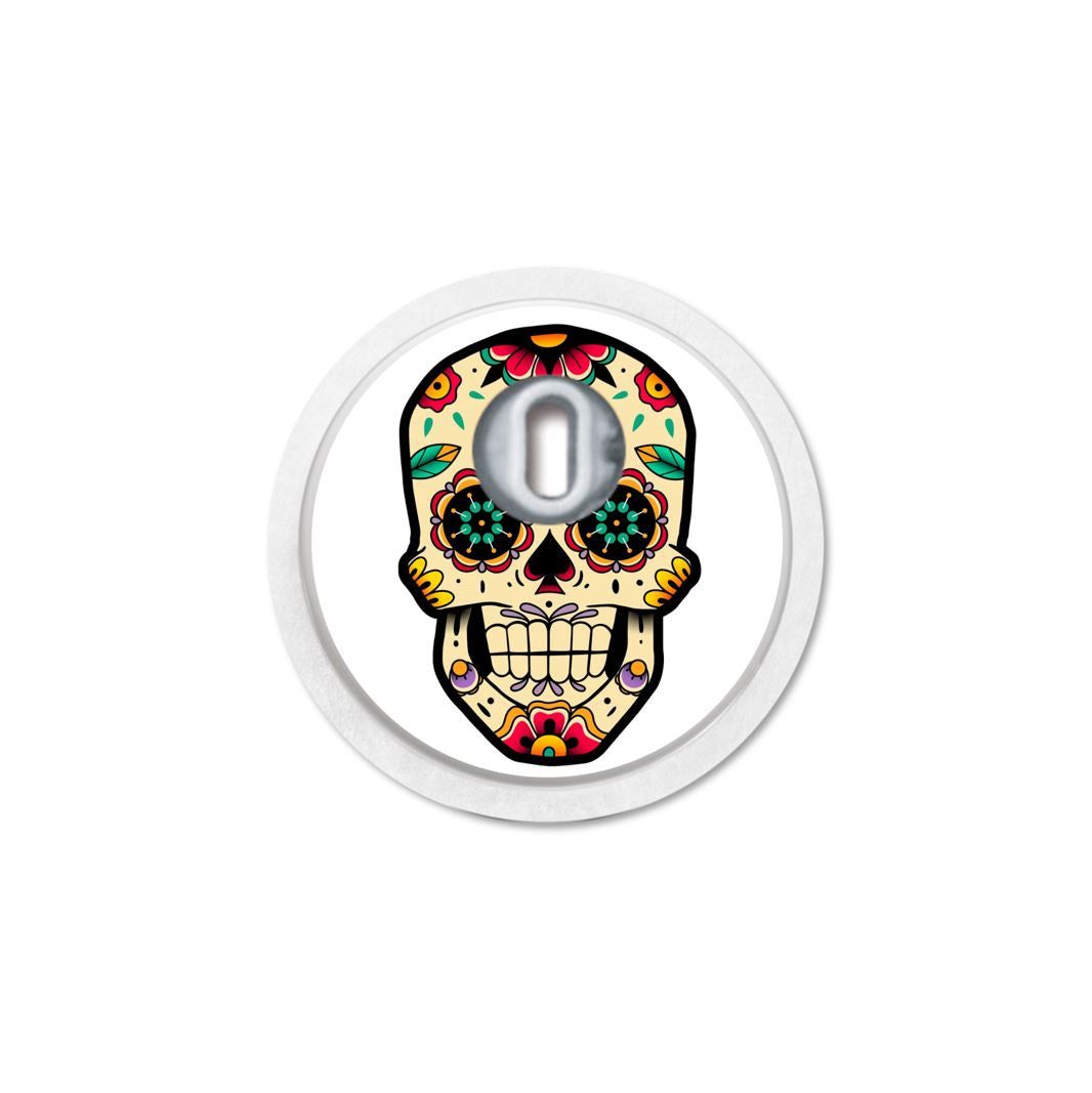 Runder Aufkleber mit Totenkopf-Design. Öffnung für Sensor. Bunte Blumenmuster. Weißer Rand.