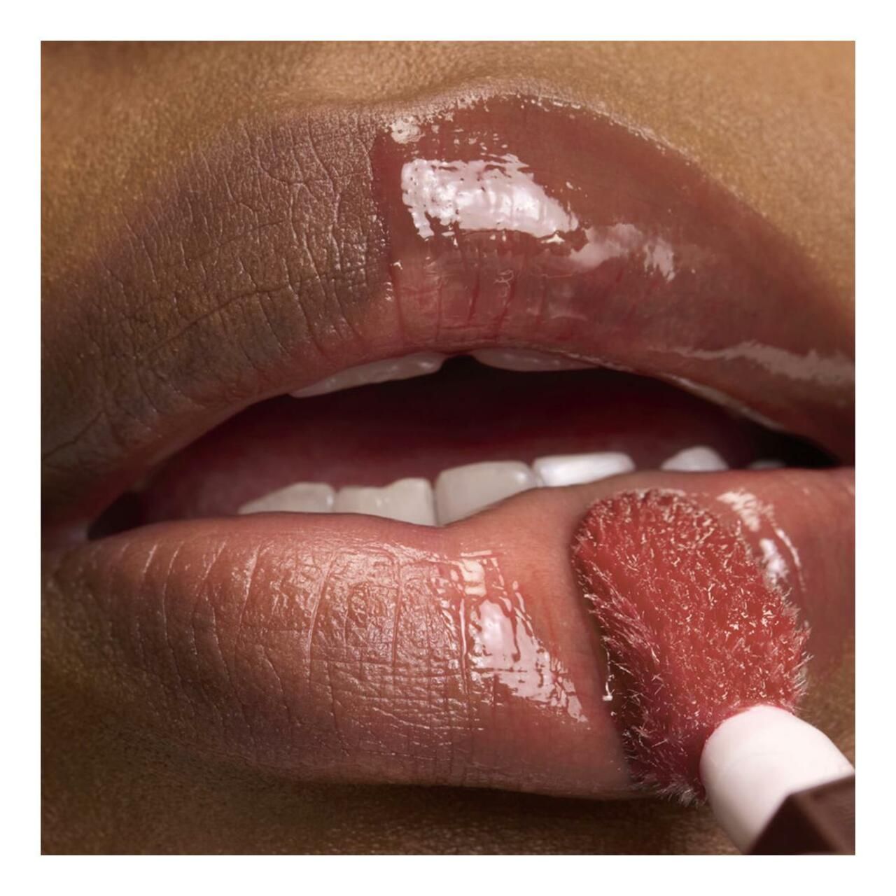 Lippen mit Lancôme Juicy Tubes Lipgloss. Applikator in Anwendung. Dunkle Haut. Glänzendes Finish.