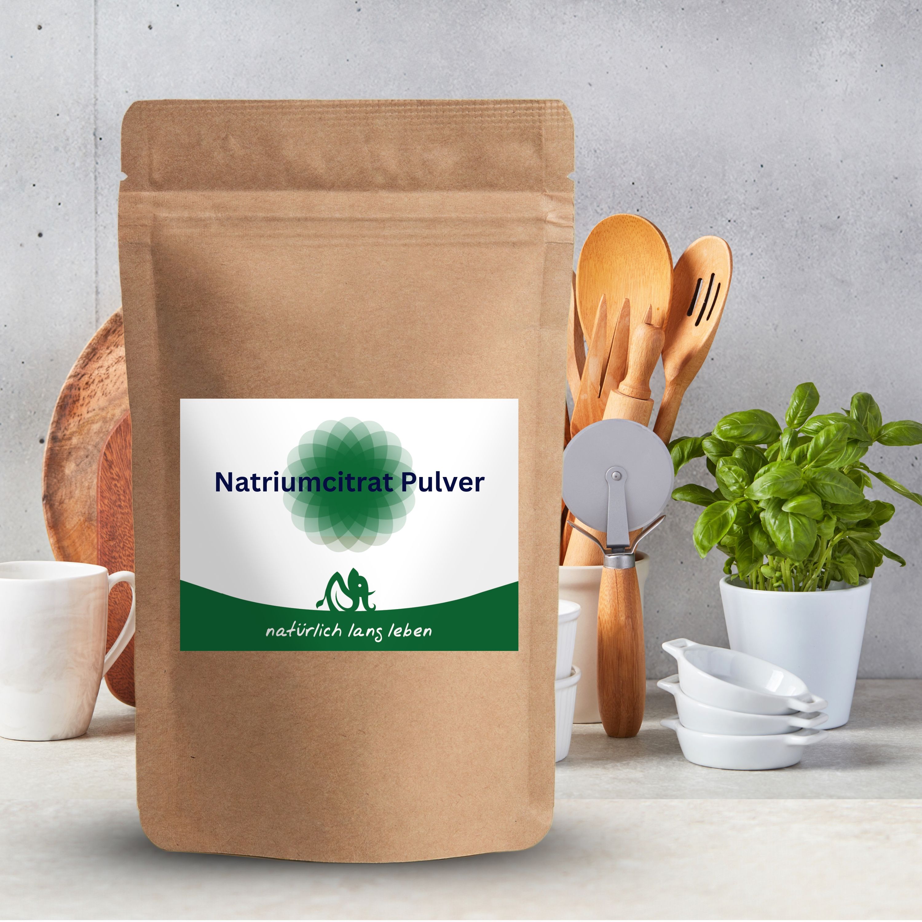 Beutel mit Natriumcitrat Pulver. Braune Verpackung mit grün-weißem Etikett. Aufschrift: Natriumcitrat Pulver und natürlich lang leben. Im Hintergrund Küchenutensilien.