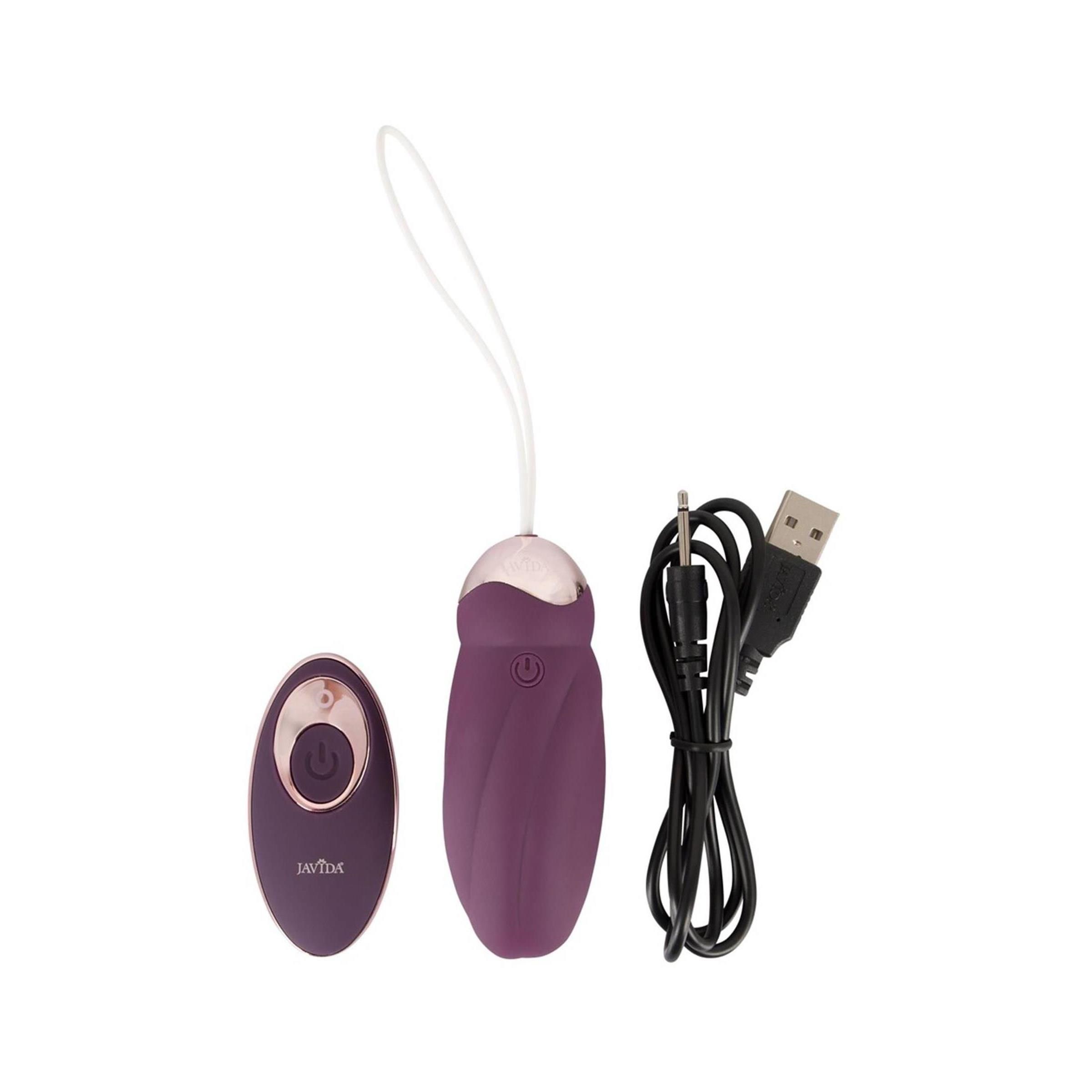 Lila Massagegerät, Fernbedienung und USB-Kabel. Goldfarbene Akzente. Weißer Hintergrund.