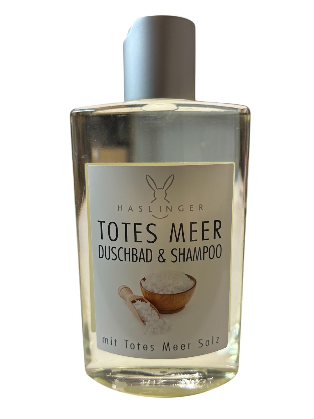 Klare Flasche mit silbernem Deckel. Etikett mit Produktnamen, Salzabbildung und Haslinger-Logo. Text: Totes Meer Duschbad & Shampoo.