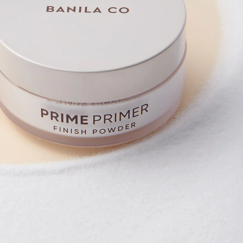 Runder, weißer Tiegel mit Deckel. Aufschrift: BANILA CO, PRIME PRIMER FINISH POWDER. Nahaufnahme.
