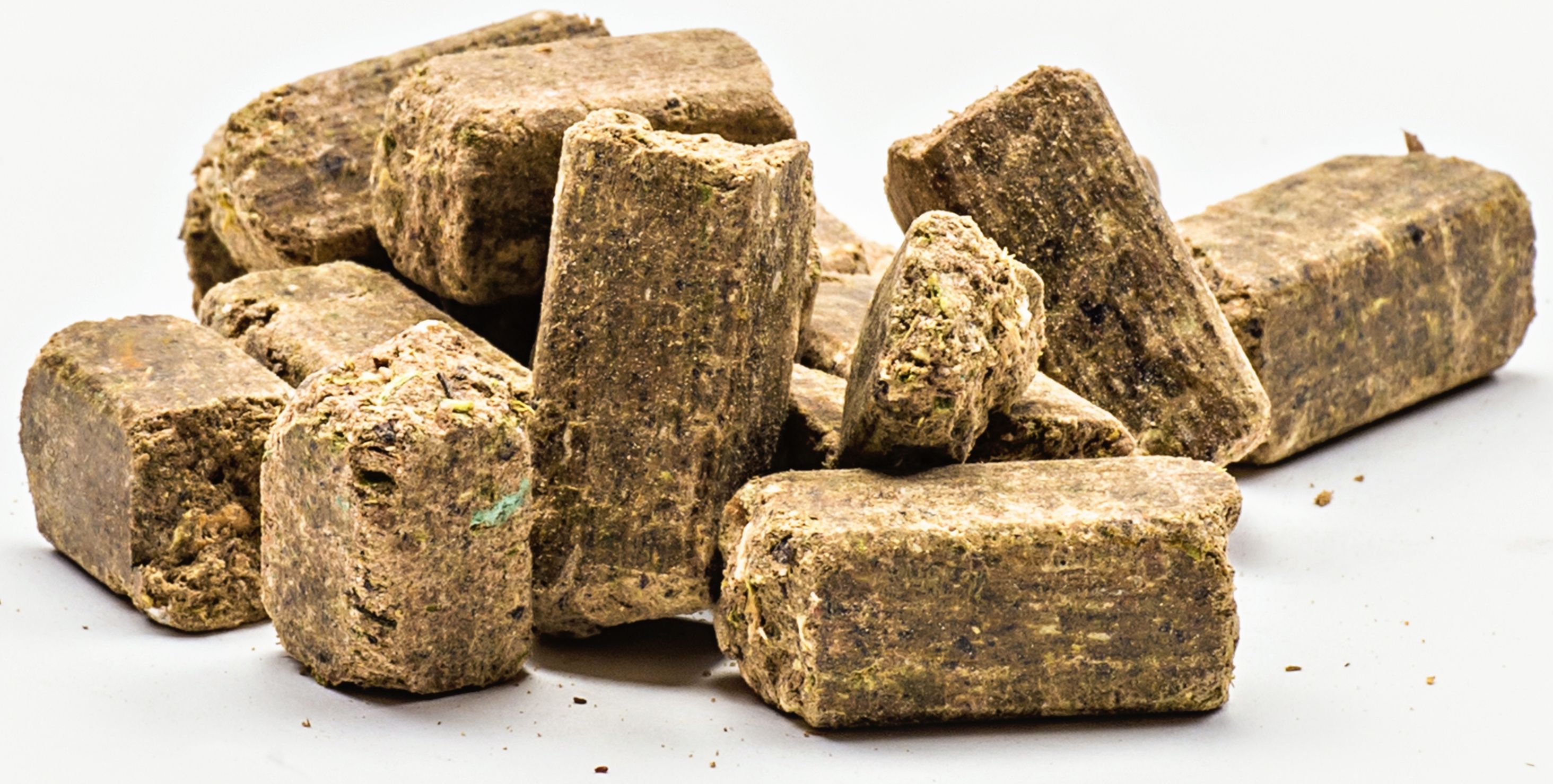 Haufen von rechteckigen, braunen Mineralfutterwürfeln. Nahaufnahme, helle Oberfläche.