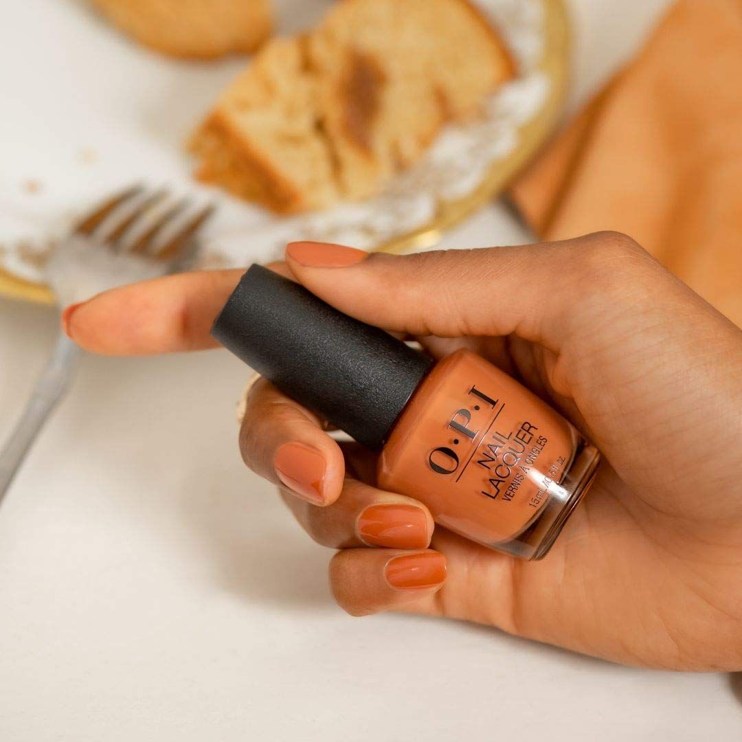 Hand hält eine OPI Nagellackflasche. Nägel sind orange lackiert. Aufschrift: OPI, Nail Lacquer.