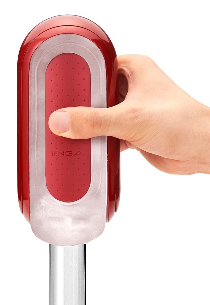 Roter TENGA Flip 0. Zylindrische Form, gehalten von einer Hand. Rote Innenfläche, transparente Hülle.