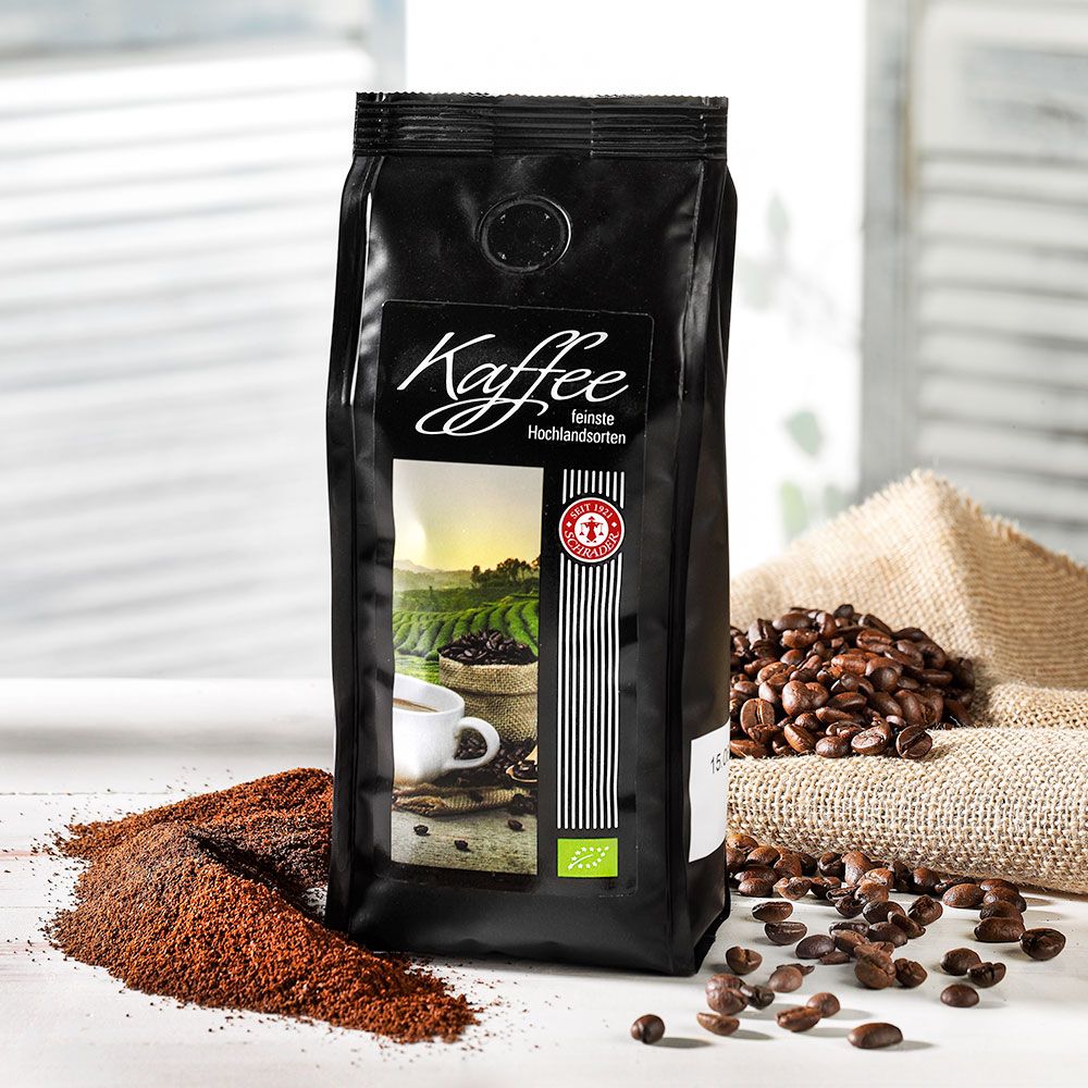 Schwarzer Kaffeebeutel mit Etikett. Aufschrift "Kaffee". Abbildung einer Tasse Kaffee und Landschaft. Bio-Siegel. Kaffeebohnen.