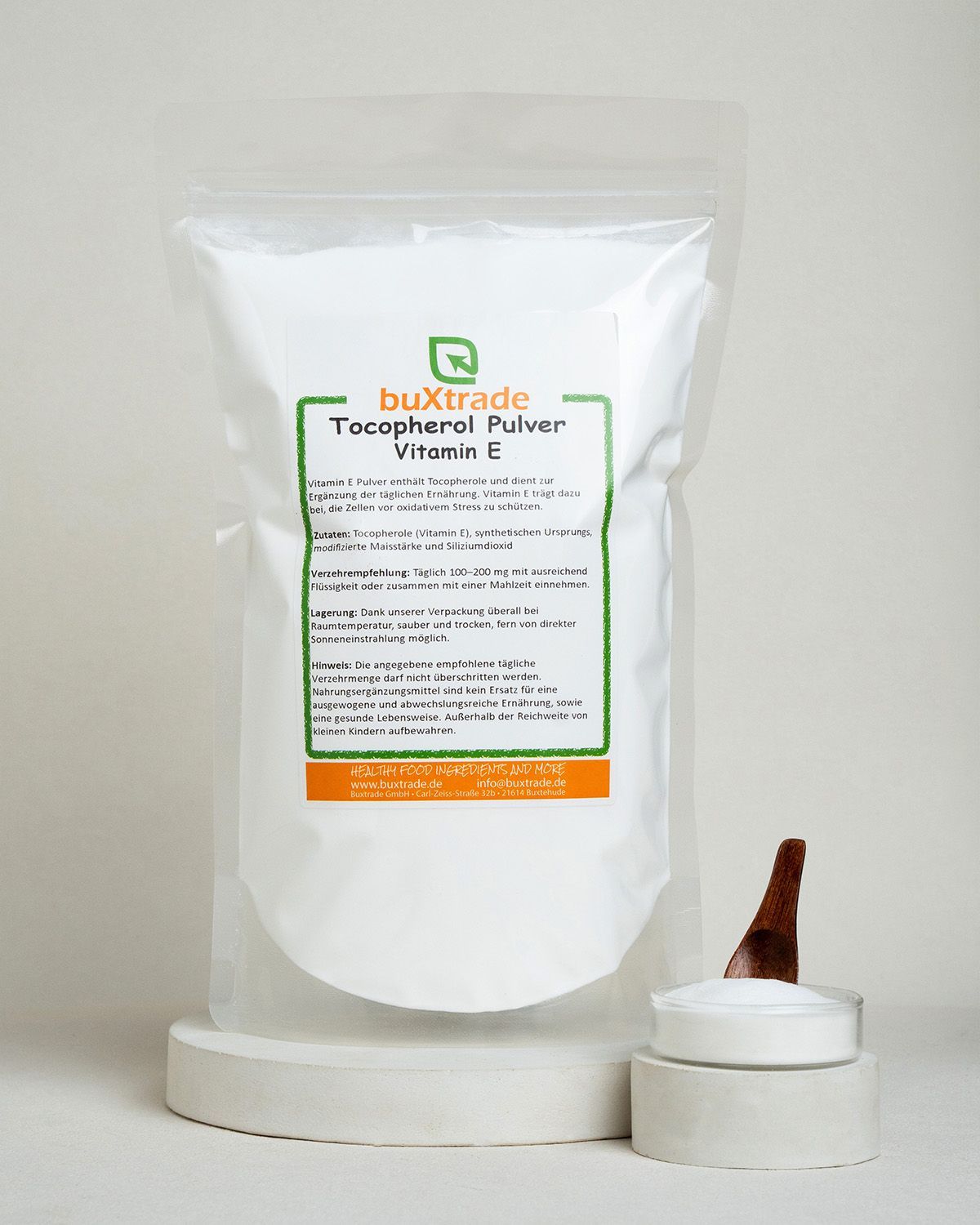Ein weißer Beutel mit Tocopherol Pulver Vitamin E von buxtrade, auf einem Betonpodest.