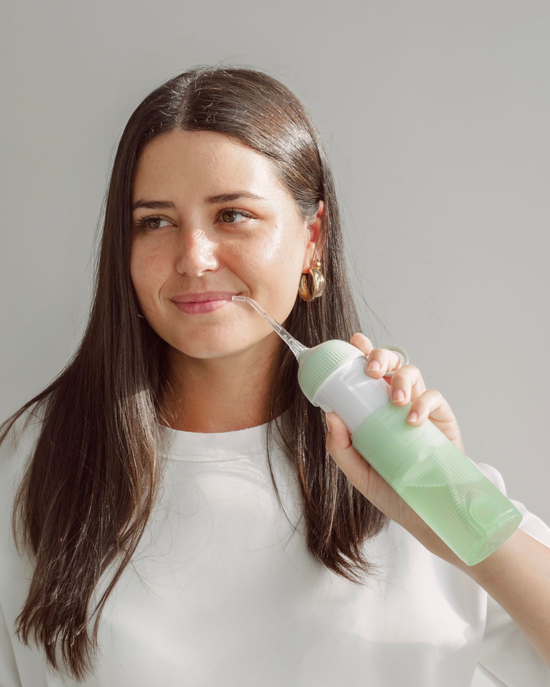 Frau mit Wasserflosser. Grüner Wasserflosser, weißer Mittelteil. Goldene Ohrringe. Helles Hintergrund.