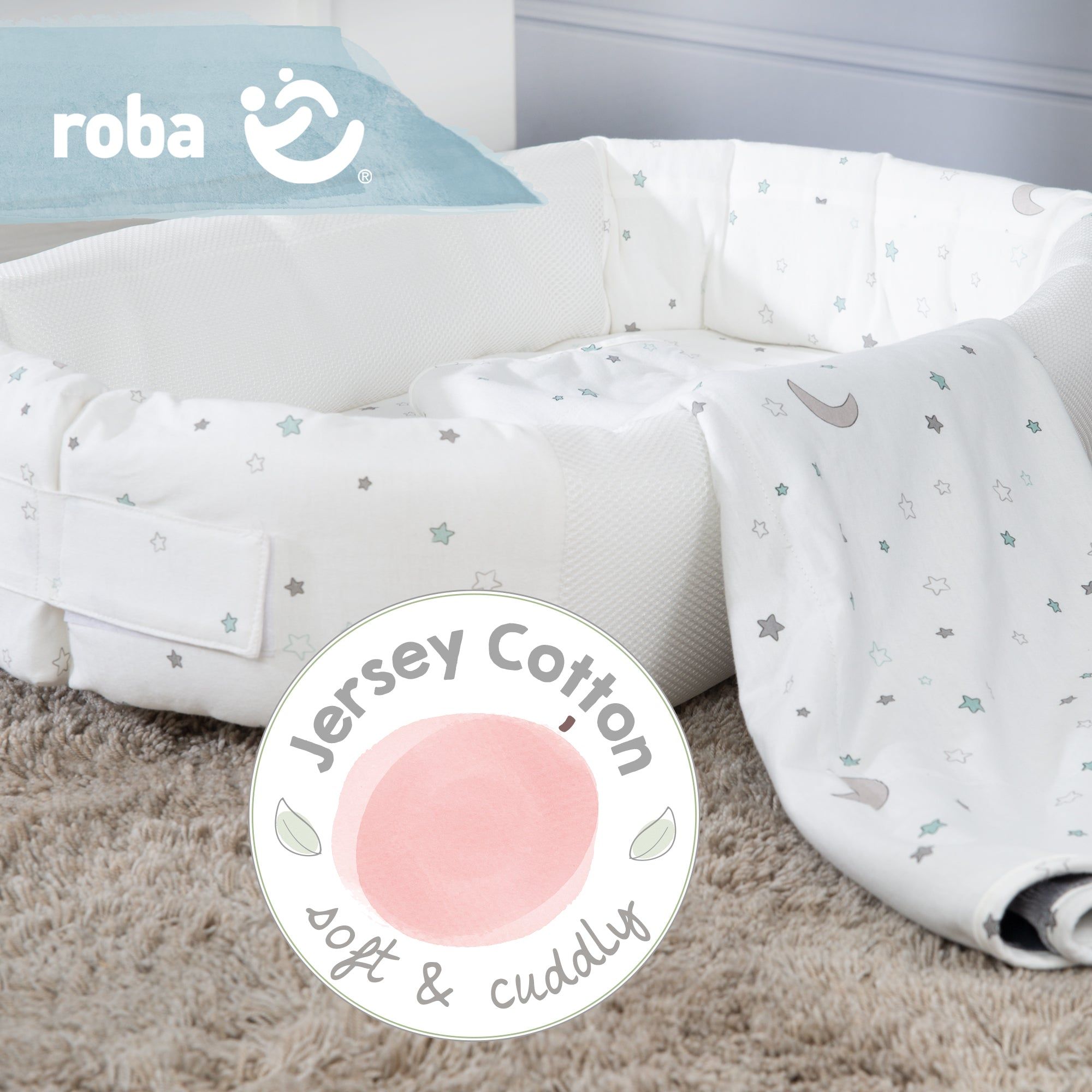 Weiße Babylounge und Decke mit Sternenmuster. Das Logo von roba ist sichtbar. Ein Etikett mit der Aufschrift Jersey Cotton ist zu sehen.