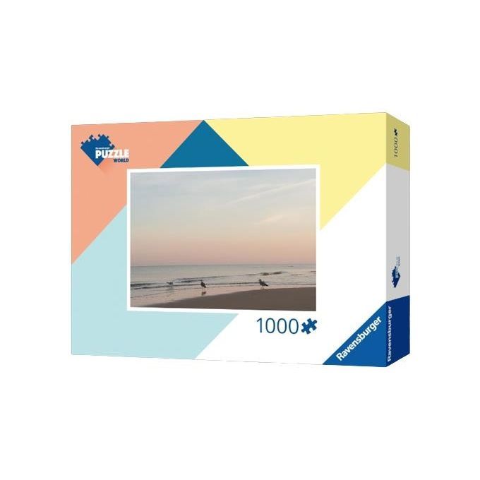 Una scatola di puzzle rettangolare di Ravensburger con un'immagine di gabbiani sulla spiaggia al tramonto. Il puzzle contiene 1000 pezzi. La scatola mostra il logo Ravensburger e il logo Puzzle World.