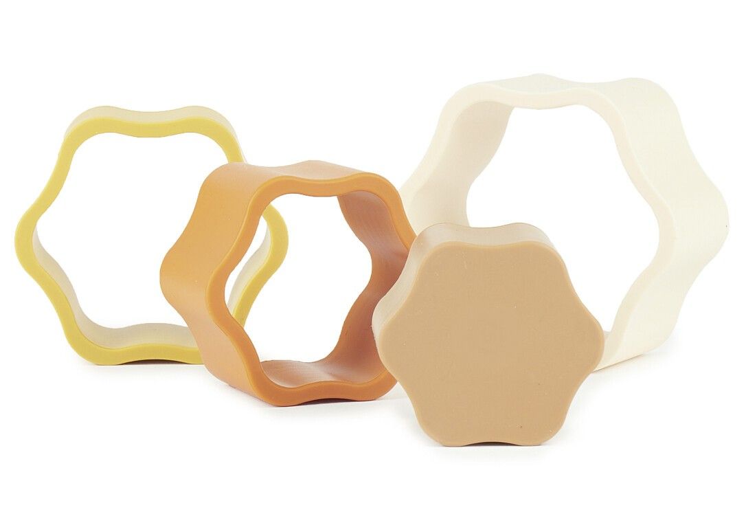 Vier Blütenförmige Elemente in Beige, Gelb, Orange und Braun. Geometrische Formen, ringförmig.