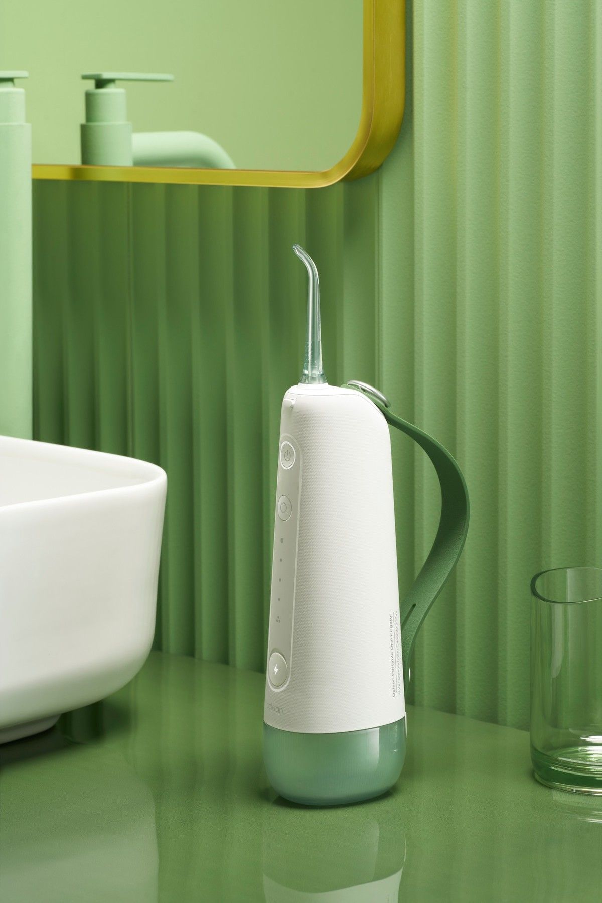 Tragbare Munddusche auf Waschbecken. Weiß-grün. Im Hintergrund Waschbecken, Spiegel und Seifenspender.