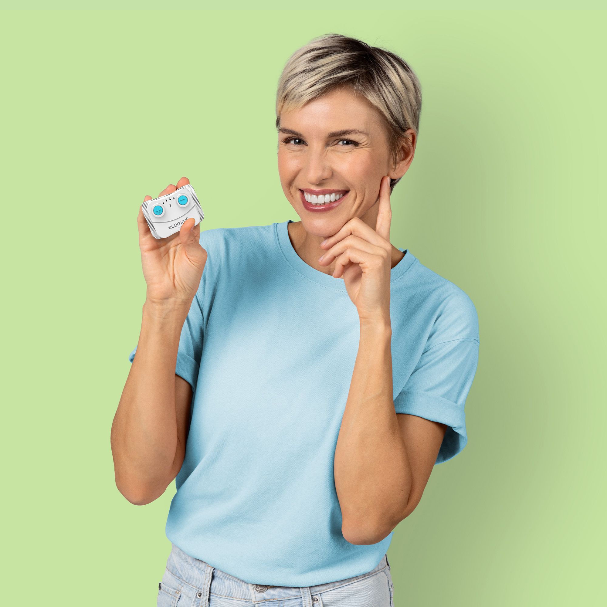 Frau hält ein weißes Gerät mit blauen Knöpfen. Sie lächelt und berührt ihr Ohr. Hintergrund: hellgrün.