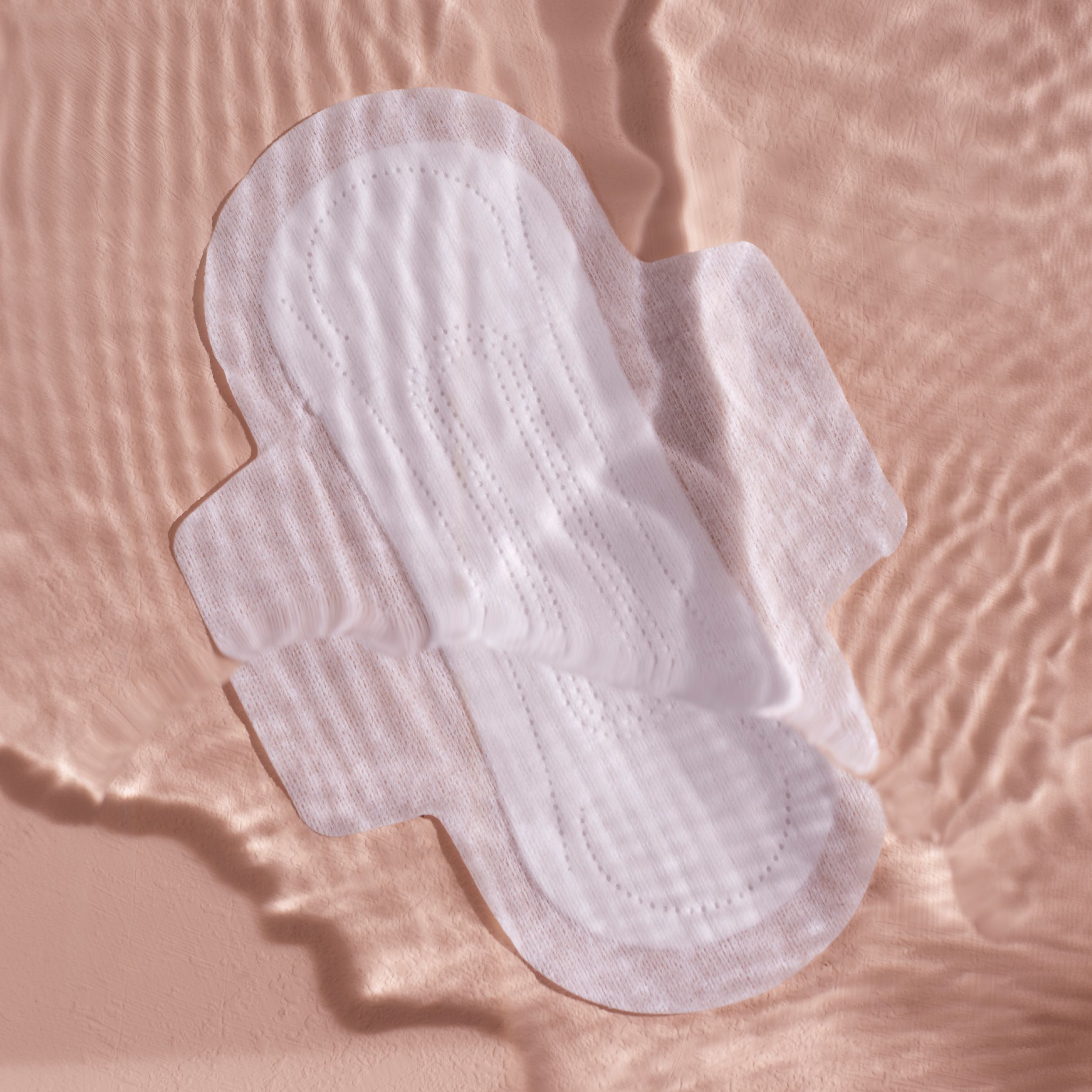 Weißes Damenbinde mit Flügeln. Auf rosa Hintergrund. Sichtbare Nähte und Struktur.