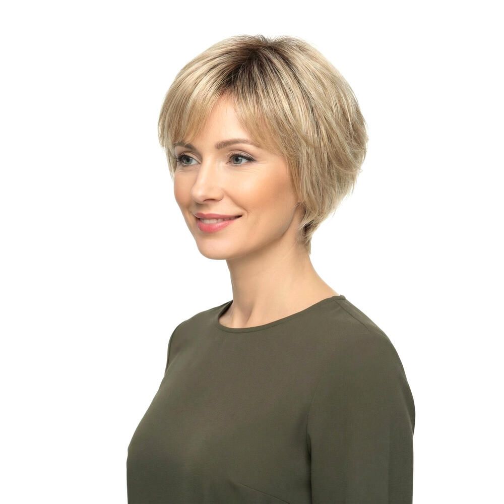 Blonde Perücke mit kurzem, gestuftem Schnitt und Pony. Die Frau trägt ein grünes Oberteil. Blickrichtung nach rechts.