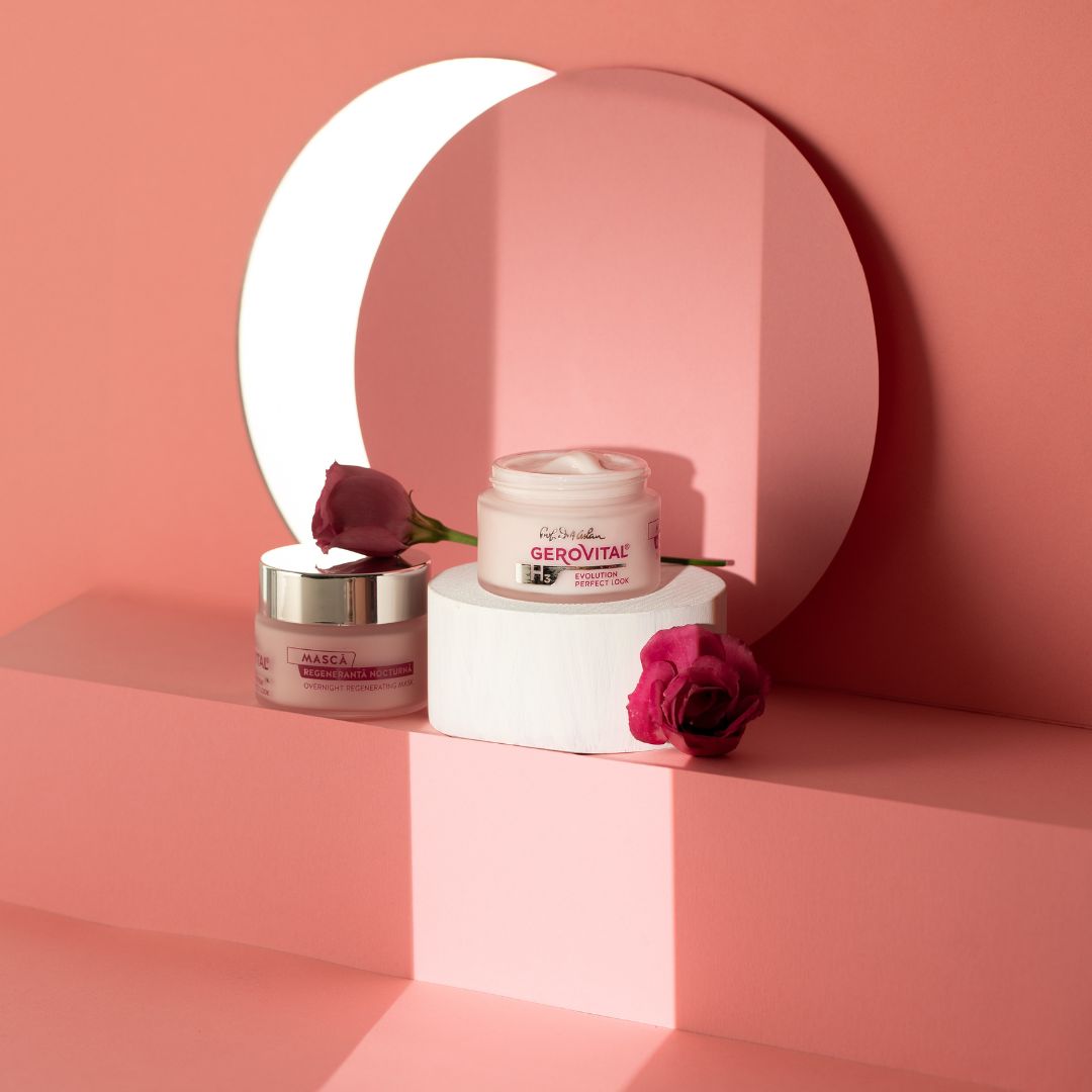 Zwei Cremetiegel auf einer weißen Plattform, umgeben von rosa Dekoration. Aufschrift: Gerovital H3 Evolution Perfect Look. Masca Regeneranta.