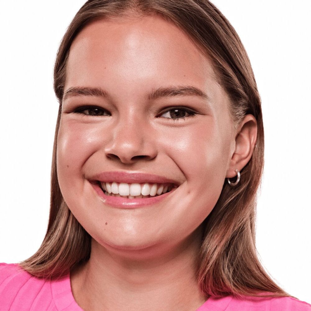 Porträt einer lächelnden Frau mit hellbraunen Haaren. Sie trägt einen rosa Pullover und silberne Ohrringe.