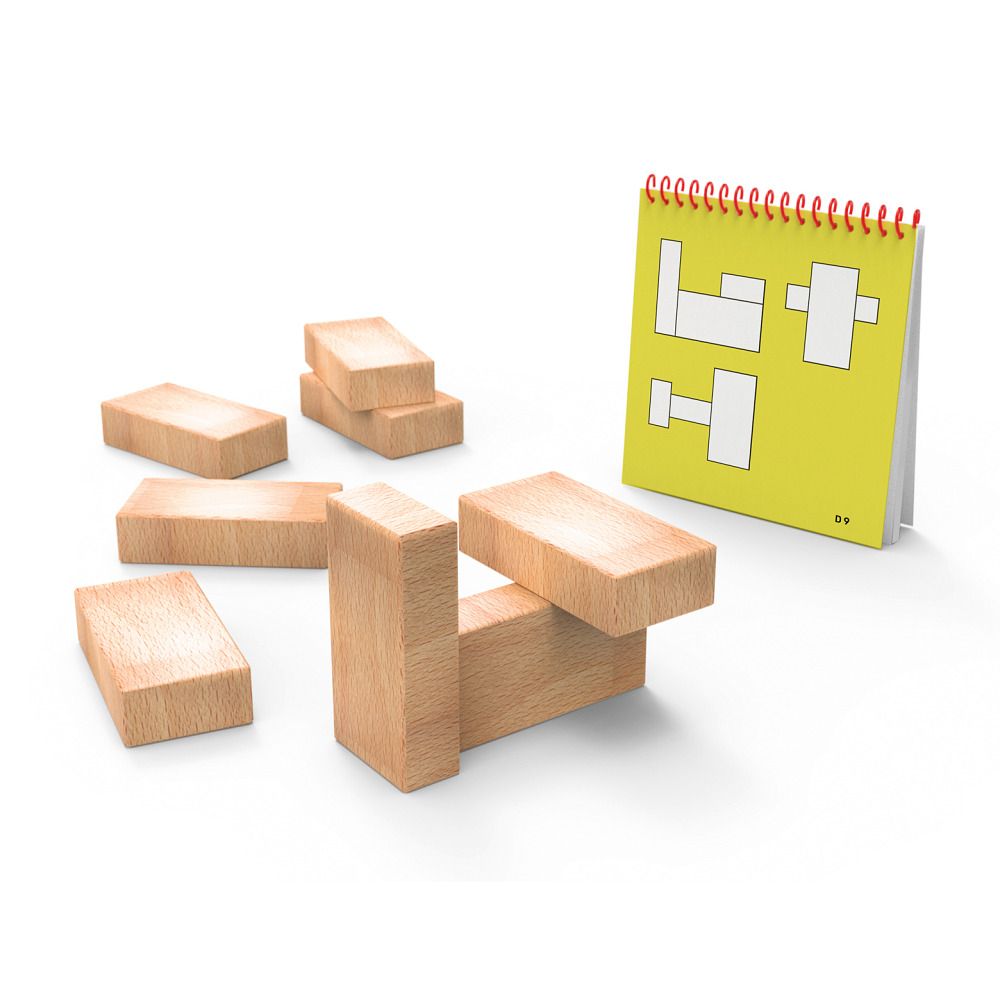 Holzbausteine und ein gelbes Heft mit roten Spiralbindung. Bausteine in verschiedenen Anordnungen. Helle Holzoberfläche.