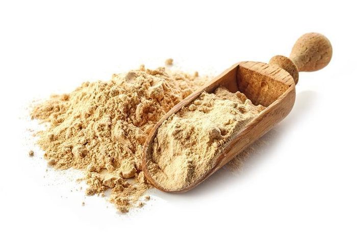 Haufen und Löffel mit buXtrade Bio Maca Pulver. Holzschaufel mit Pulver daneben. Helles Pulver.