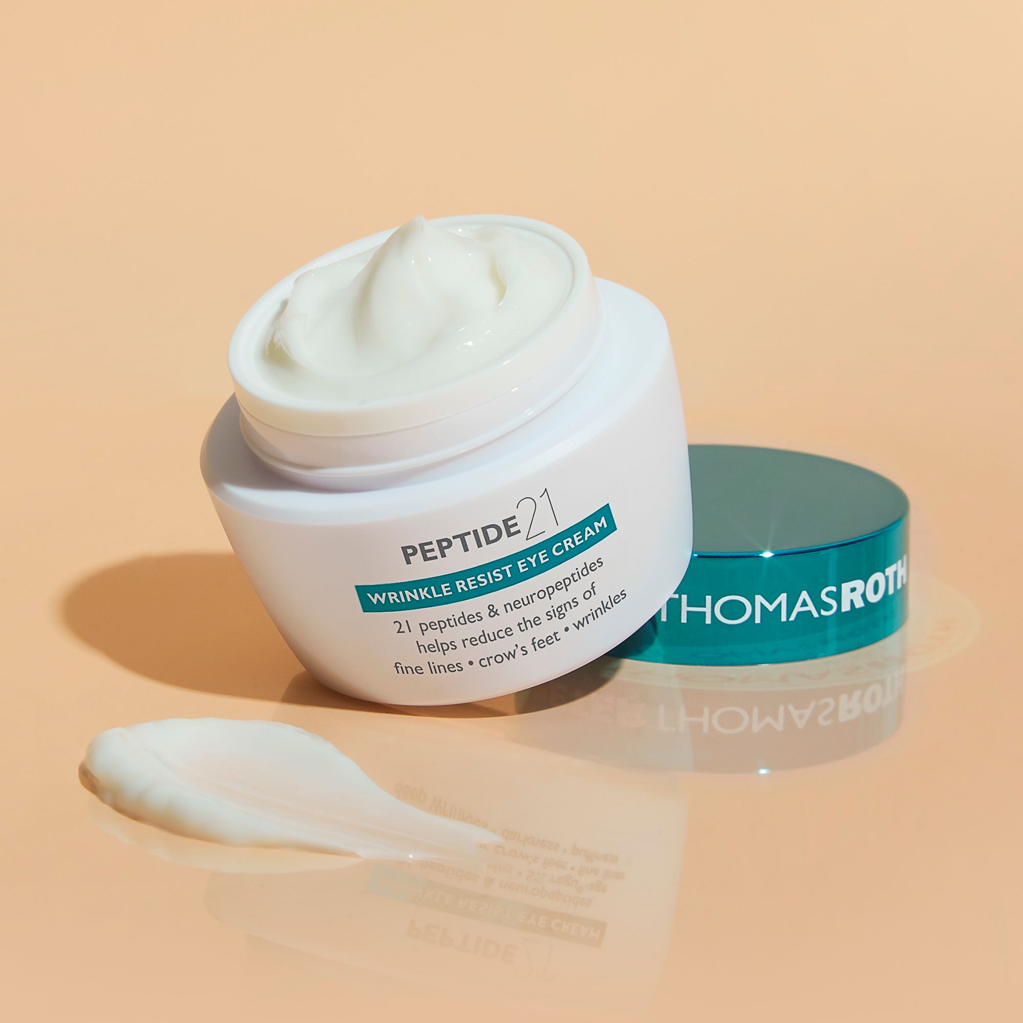 Peter Thomas Roth Peptide 21® Wrinkle Resist Eye Cream. Geöffneter Tiegel, Creme und Deckel. Creme-Klecks daneben.