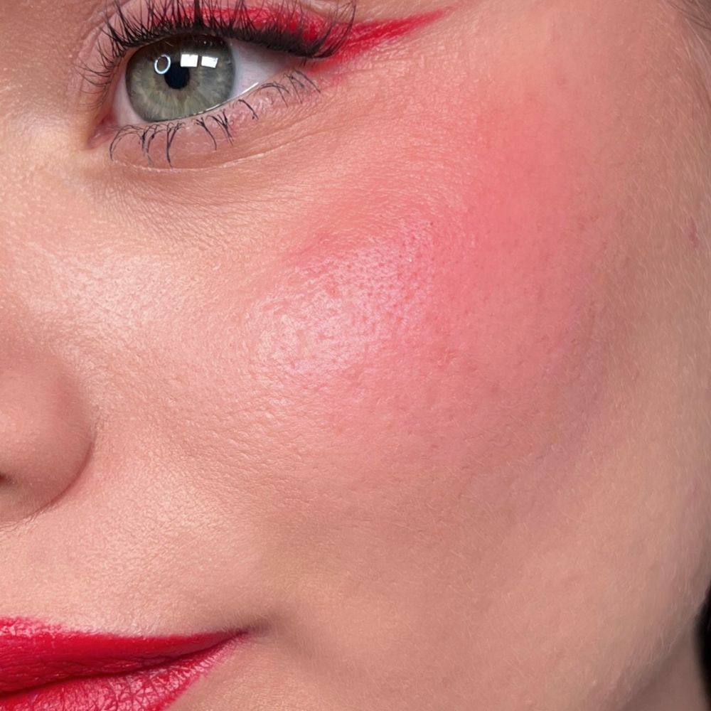 Nahaufnahme eines Gesichts mit rotem Lippenstift, Eyeliner und Rouge. Grünes Auge. Produkt: ALL TIGERS.