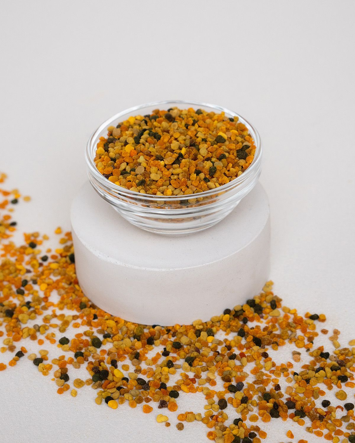 Glas Schale mit Bltenpollen auf wei?em Sockel. Streuung von Pollen auf der Oberfl?che.