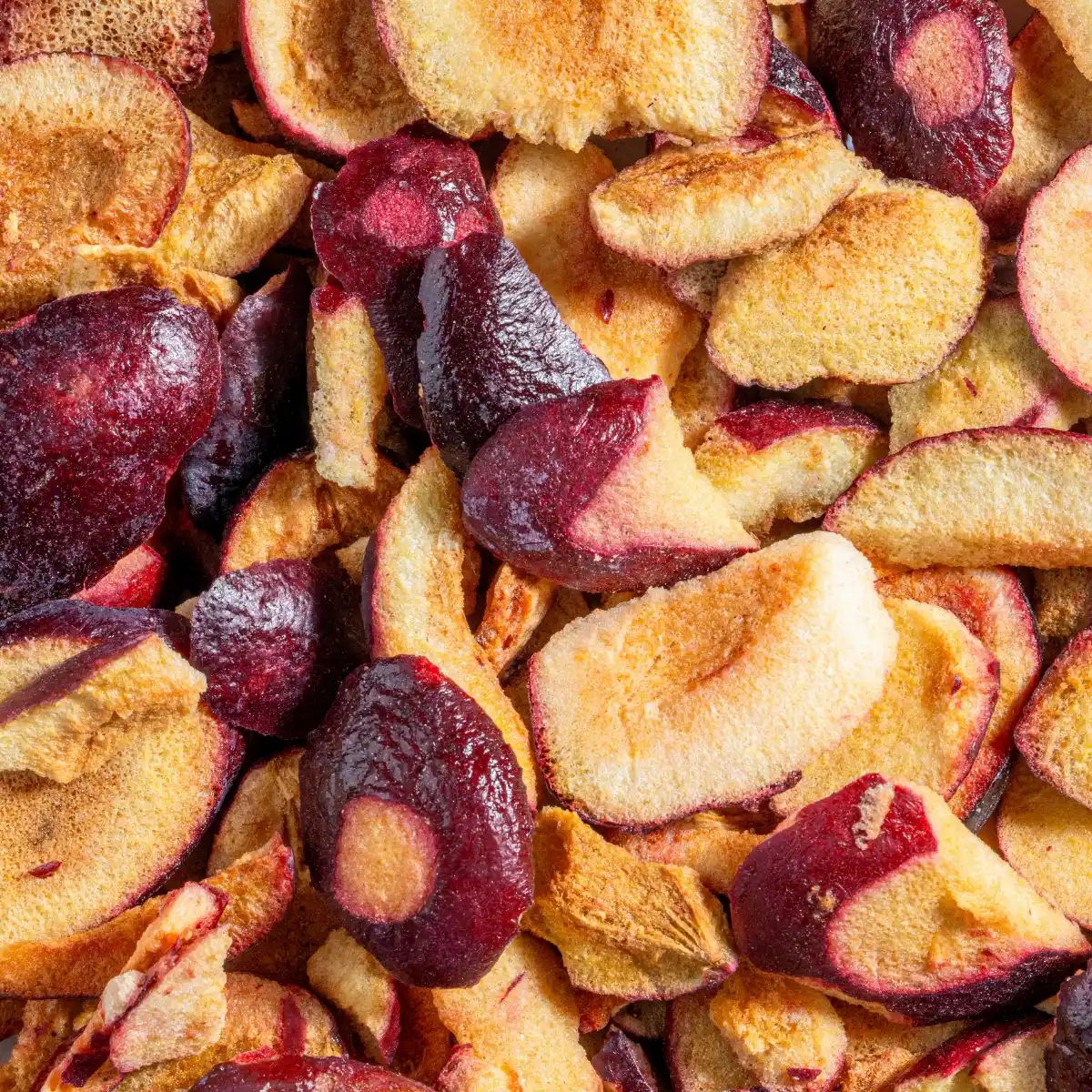 Nahaufnahme von gefriergetrockneten Pflaumen. Gelbe und rote Farbtöne. Einige Stücke sind ganz, andere in Scheiben geschnitten.
