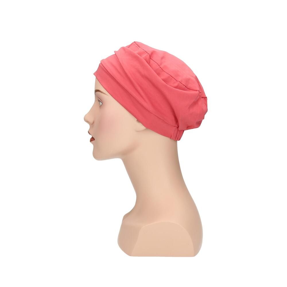 Korallenfarbener Turban auf Büste. Stoffhaube mit Faltenwurf. Seitenansicht.