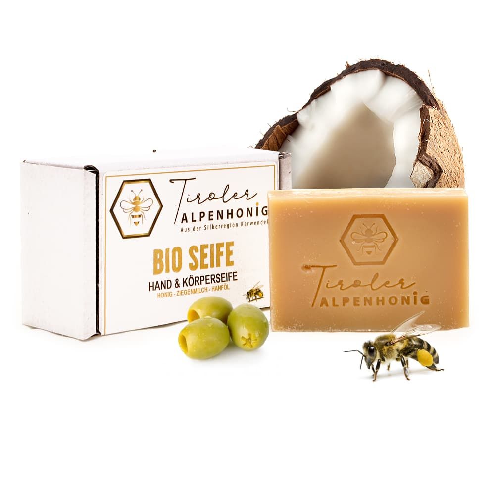 Bio Seife, rechteckig, mit Logo und Schriftzug. Neben Verpackung, Kokosnuss, Oliven und Biene.