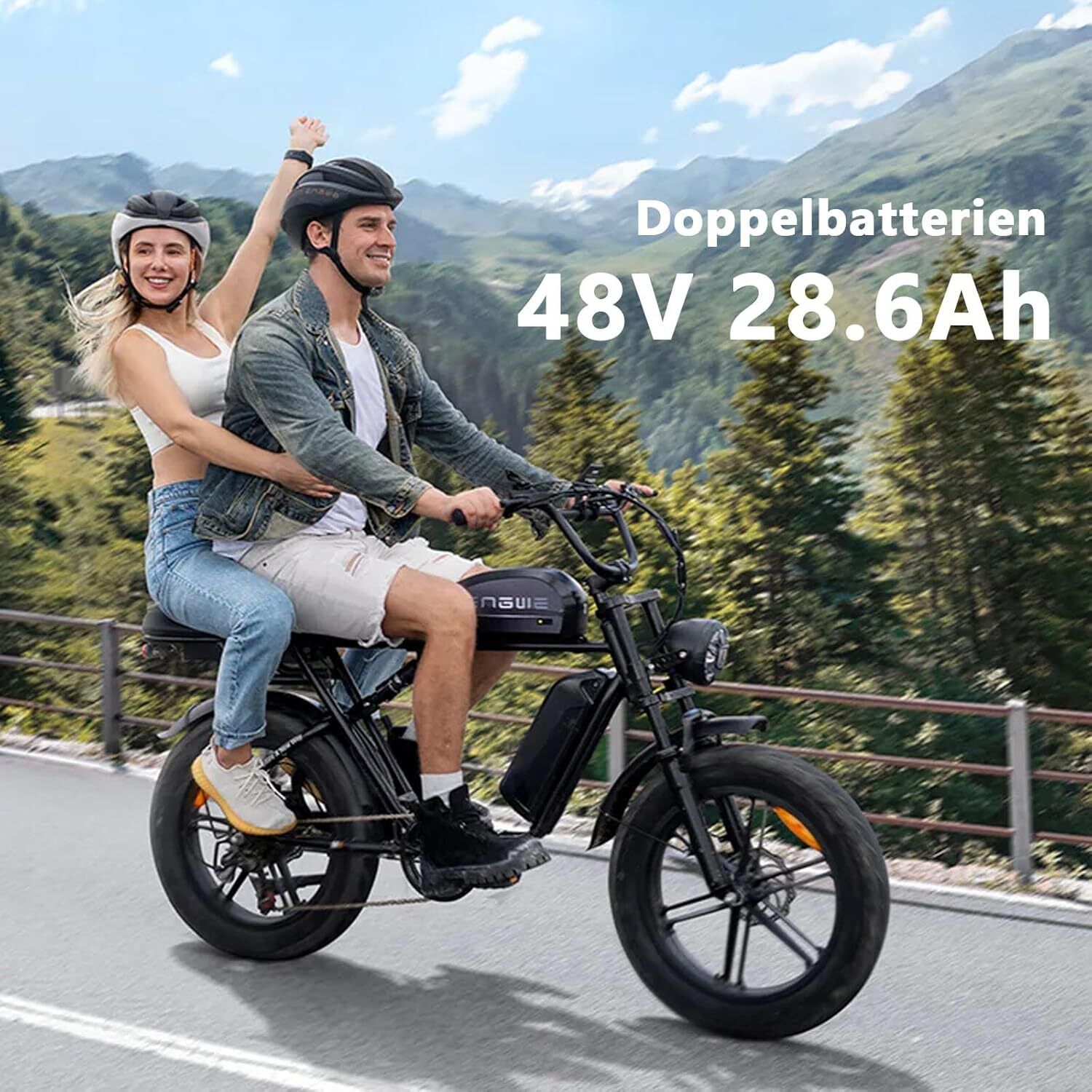Schwarzes E-Bike mit zwei Personen. Auf dem Rahmen steht "Doppelbatterien 48V 28.6Ah". Beide tragen Helme. Im Hintergrund Berge.