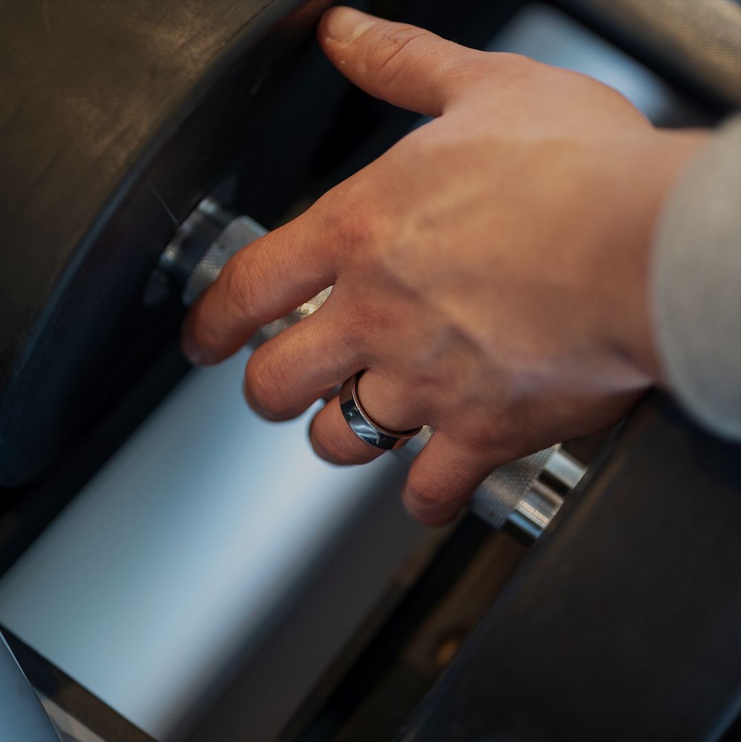 Hand mit Ring am Finger. Der Ring ist schwarz und silberfarben.