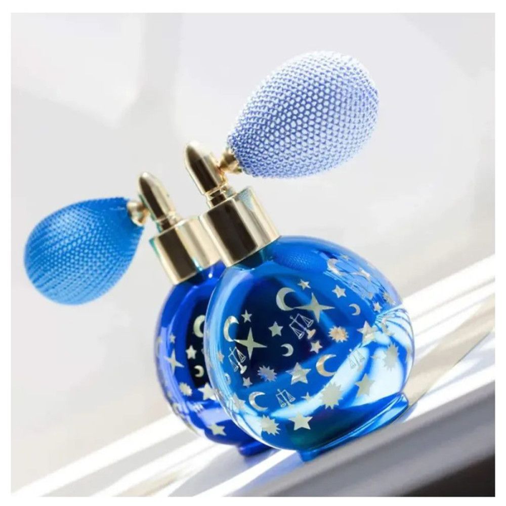 Zwei blaue Flakons mit goldenen Verschlüssen und blauen Zerstäubern. Sterne und Monde auf den Flakons.