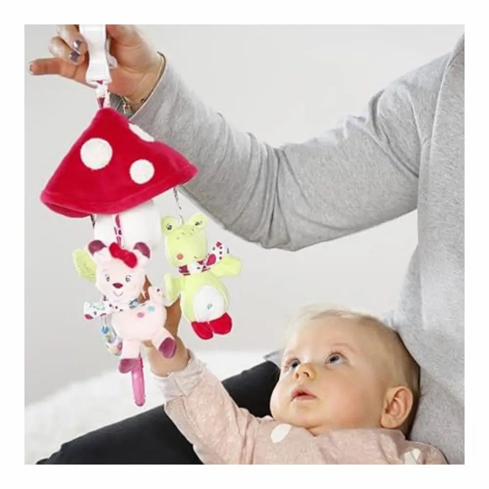 Baby und Mobile. Mobile mit Pilz, Reh und Frosch. Person hält das Mobile über dem Baby.