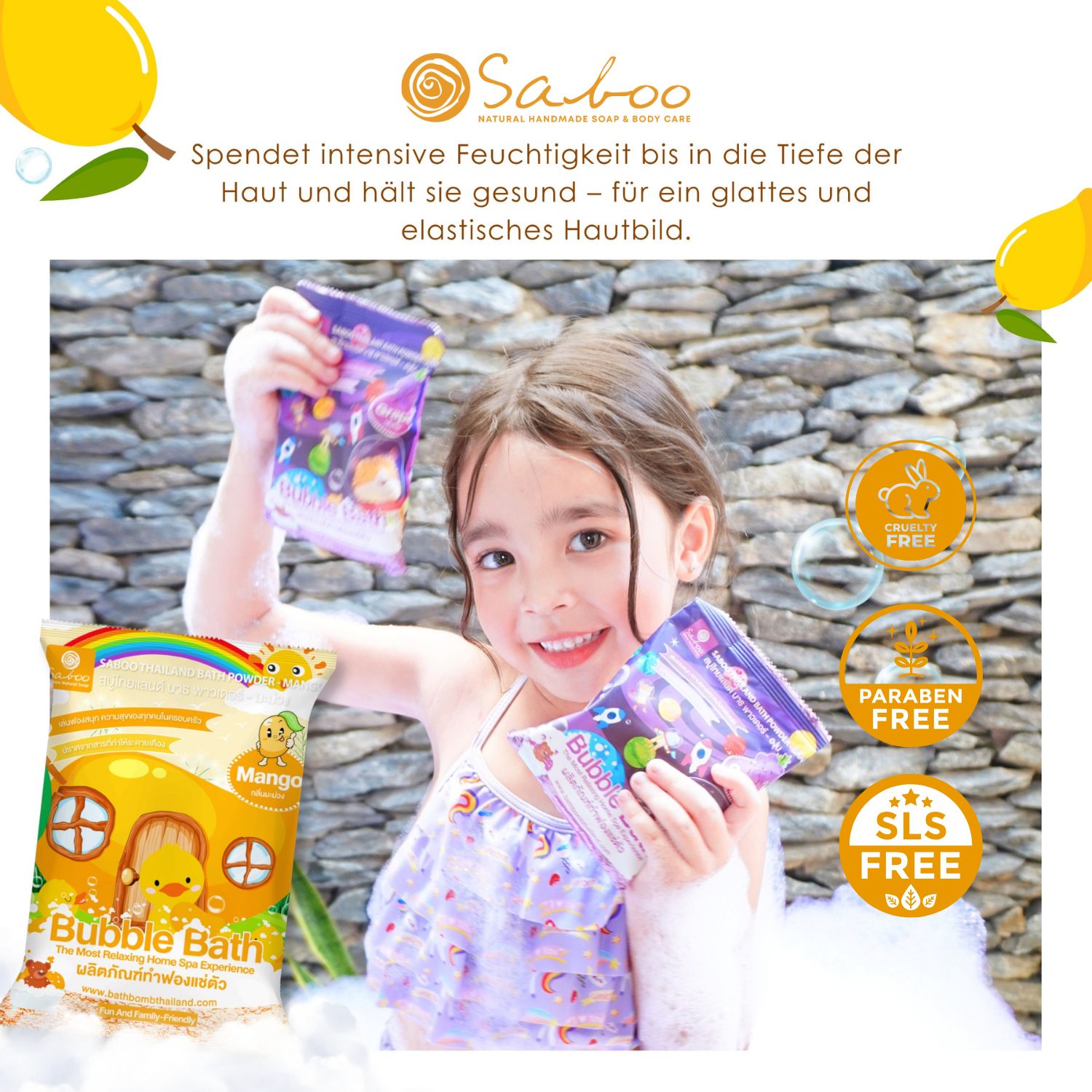 Mädchen hält zwei Beutel SABOO Schaumbad Pulver. Gelbe Verpackung mit Mango-Motiven. Hintergrund: Steinmauer.