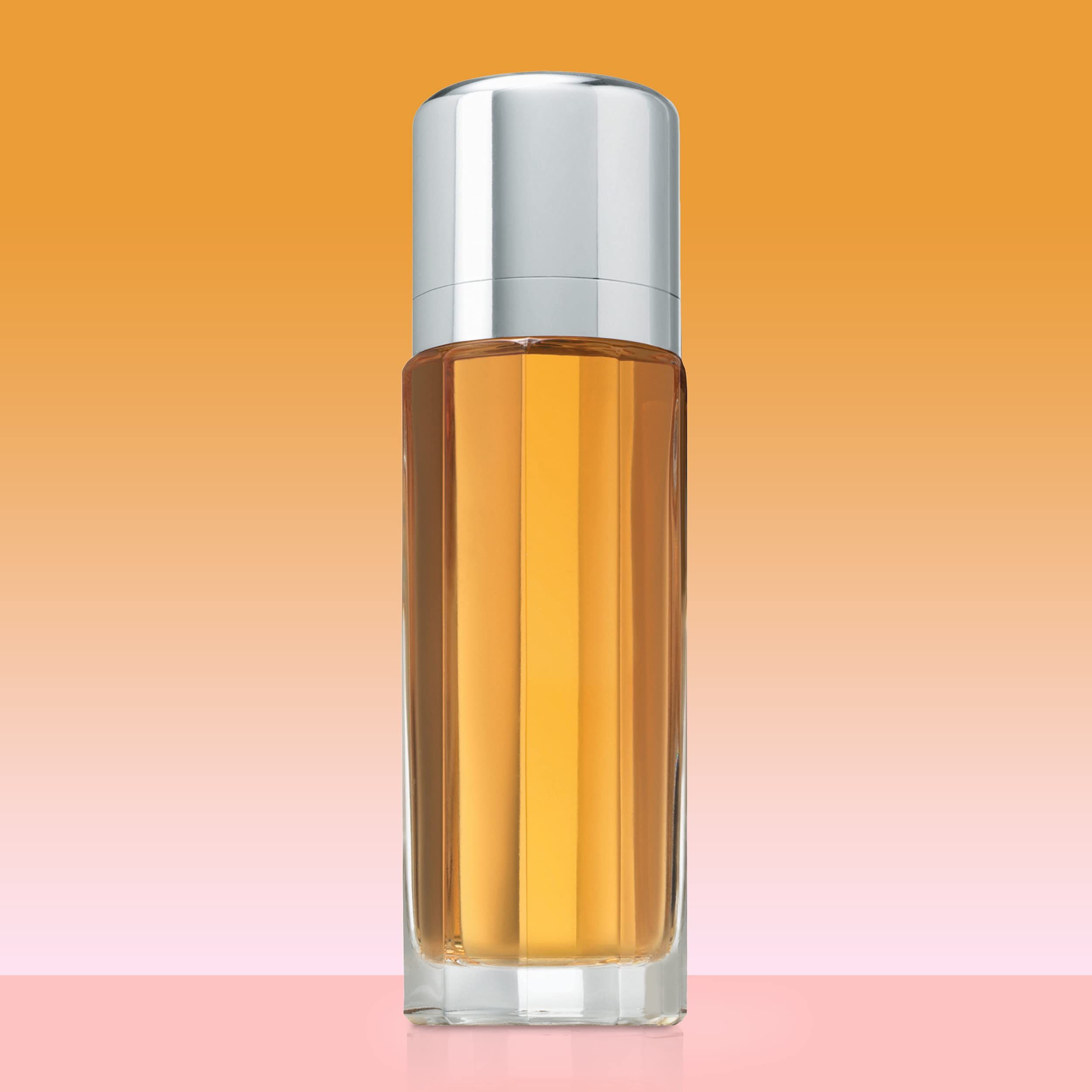 Zylindrische Parfümflasche mit silbernem Deckel. Bernsteinfarbene Flüssigkeit. Auf rosa-orangefarbenem Hintergrund.