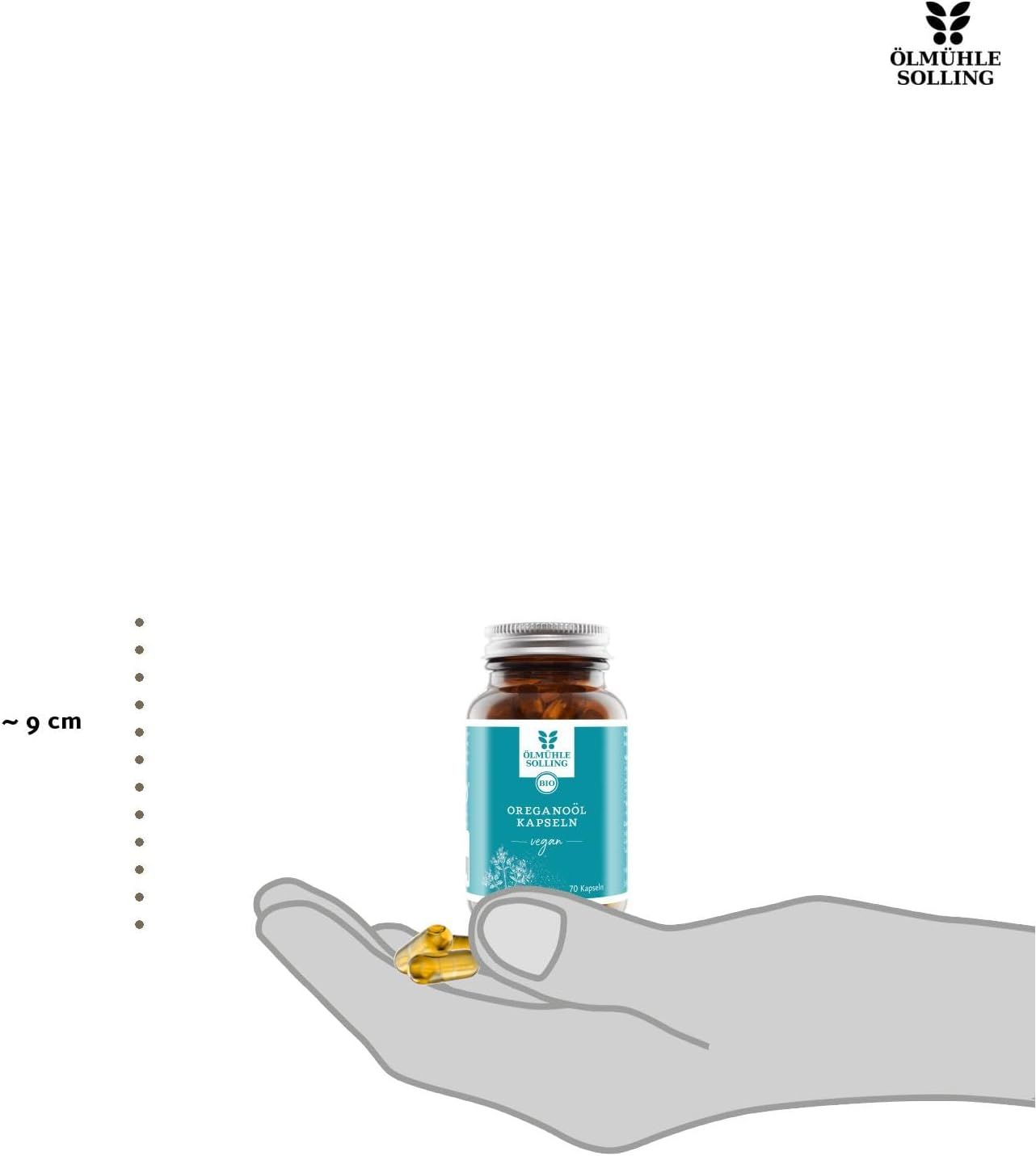 Eine Hand hält eine Flasche mit Oreganoöl-Kapseln und einige Kapseln.