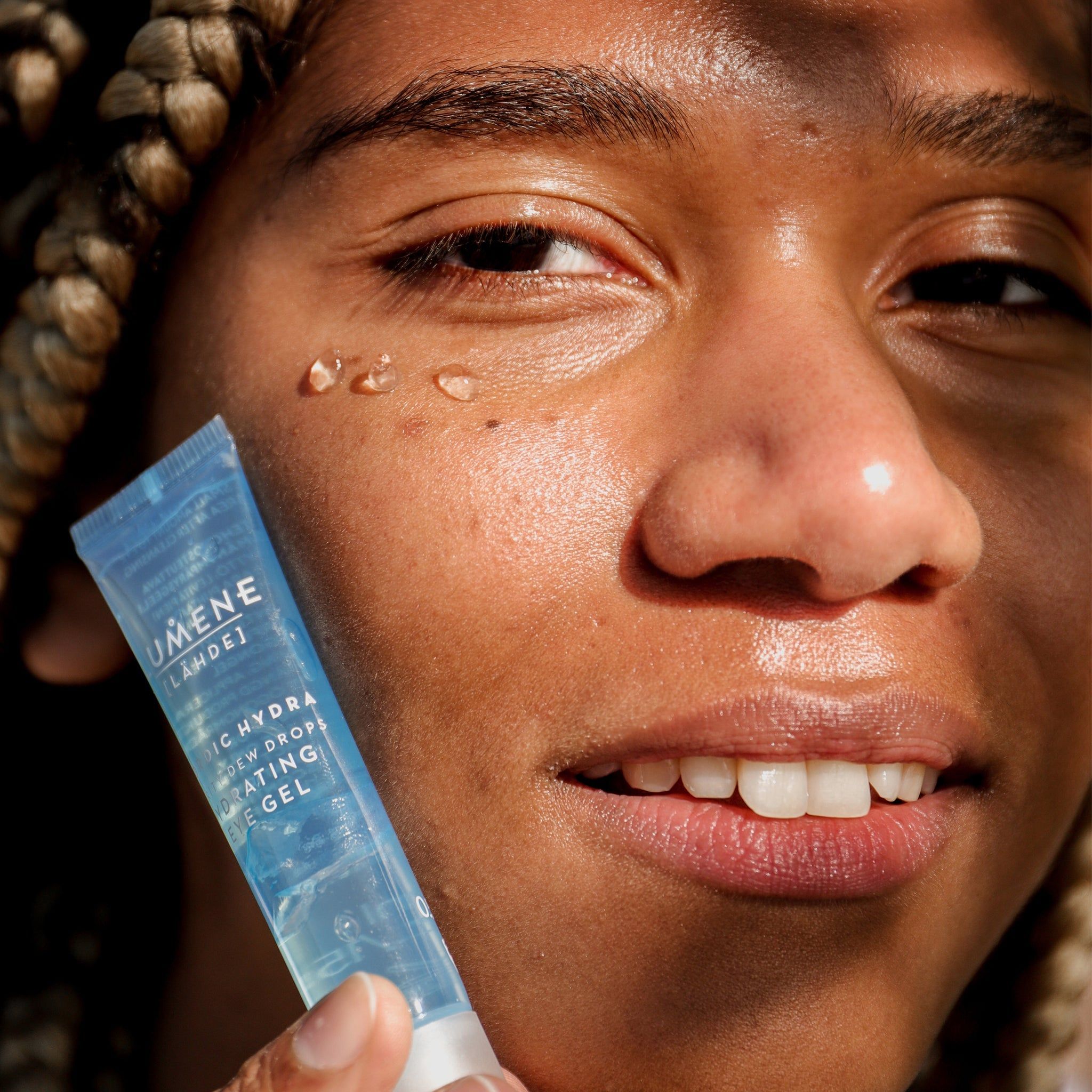 Person hält Tube vor Gesicht. Aufschrift: Lumene [LAHDE] Nordic Hydra Purity Dew Drops Hydrating Eye Gel. Gel-Tropfen auf Haut.