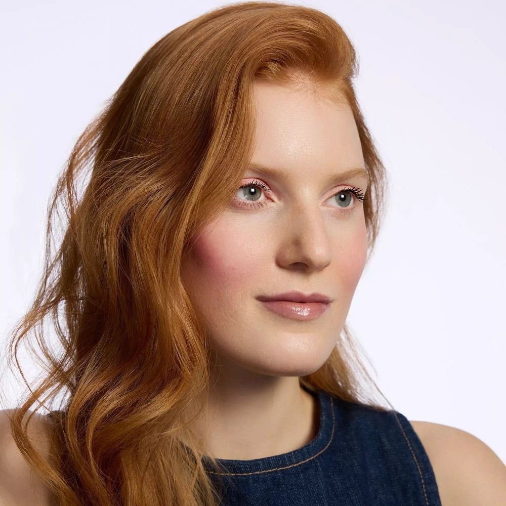 Frau mit roten Haaren und dezentem Make-up, blauer Jeans-Oberteil.
