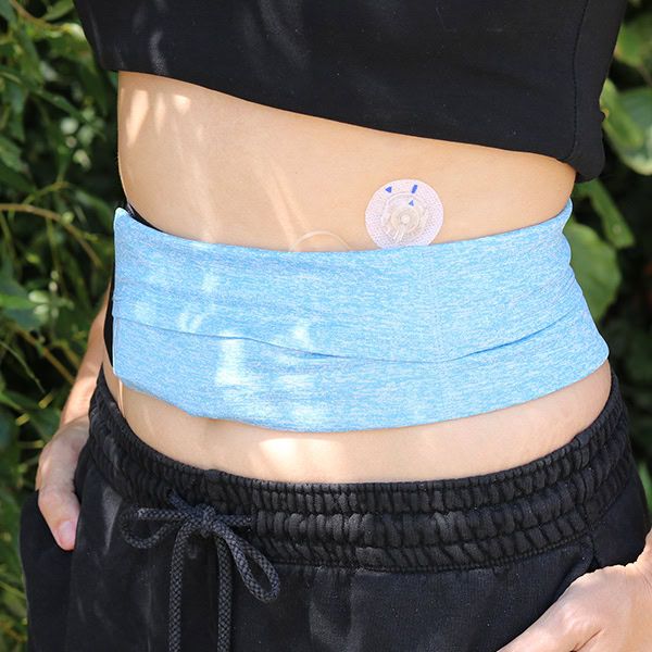 Person trägt einen blauen Bauchgurt. Ein Gerät ist am Bauch befestigt.