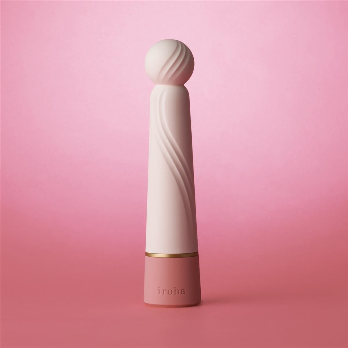 Weiß-rosa Vibrator mit gerillter Oberfläche und rosa Basis. Goldener Ring. iroha-Logo.
