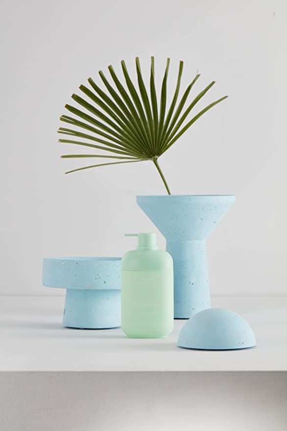 Grüne HAAN Handseife mit Verbena-Duft, umgeben von blauen Objekten und einem Blatt.