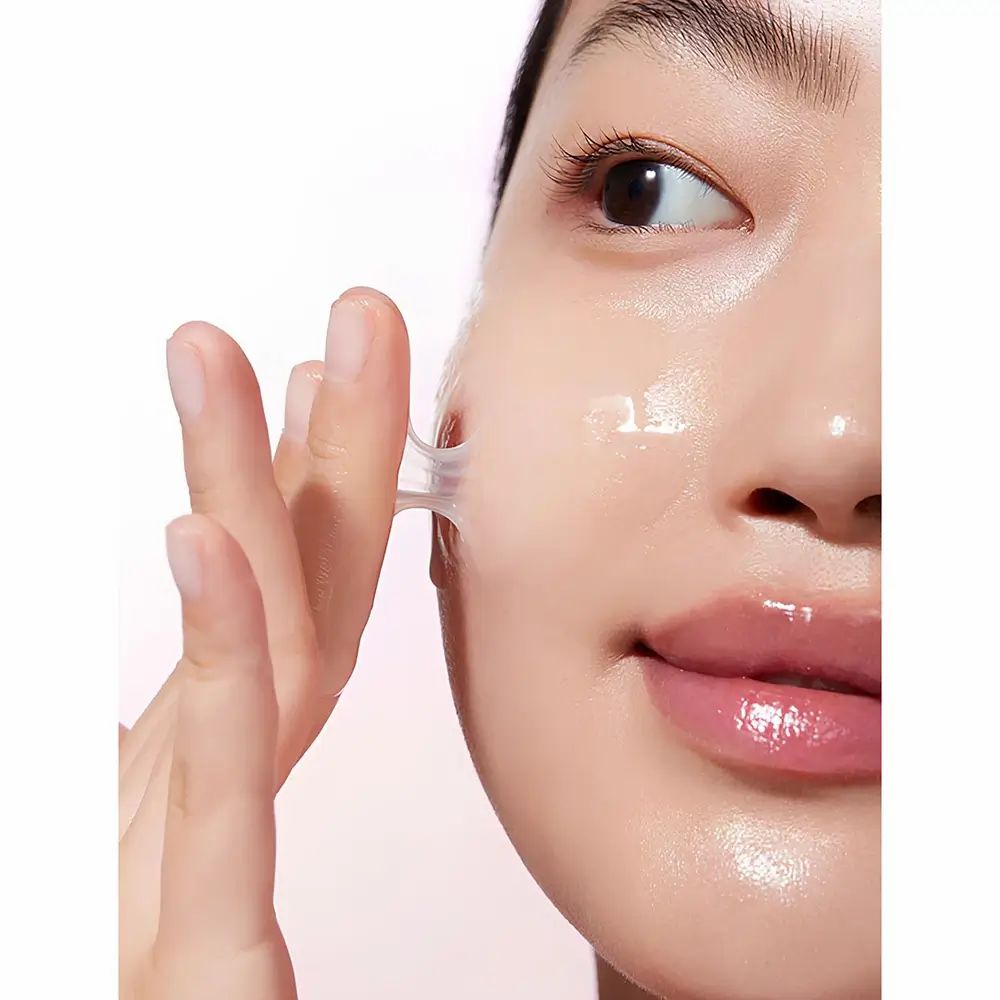 Nahaufnahme einer Frau, die Serum auf ihr Gesicht aufträgt. Serum ist sichtbar.