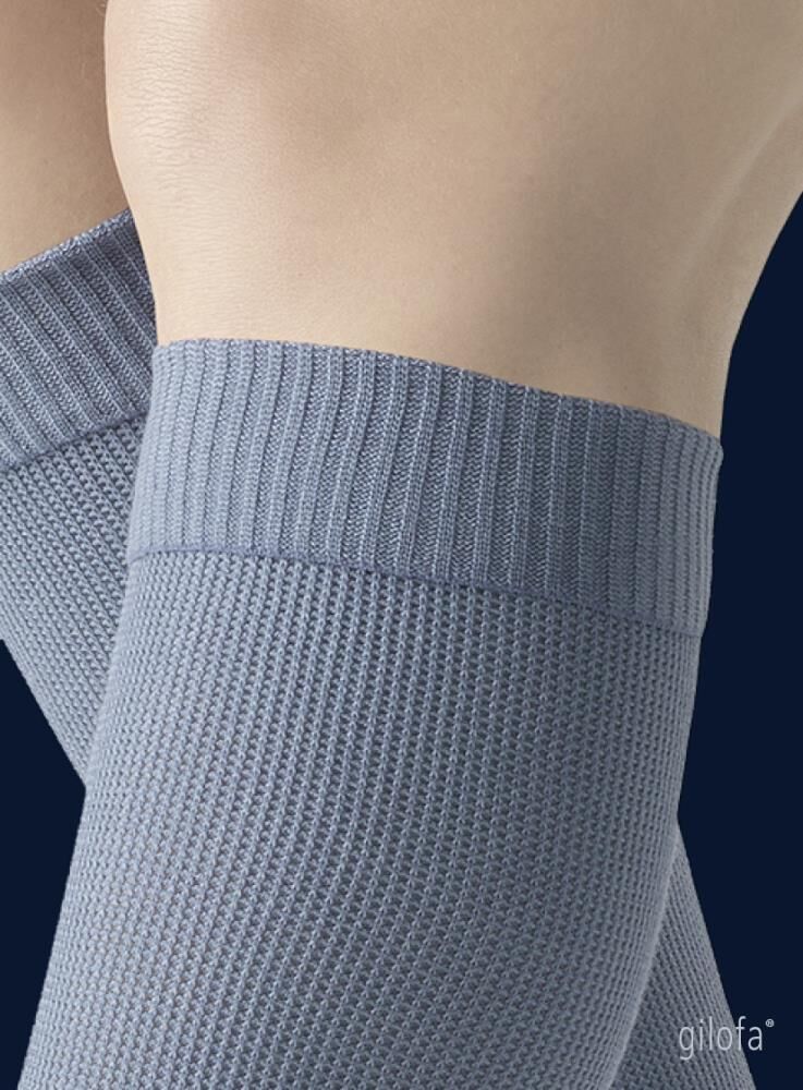 Detailansicht des oberen Teils eines hellgrauen Kompressionsstrumpfes. Rippstrickmuster.