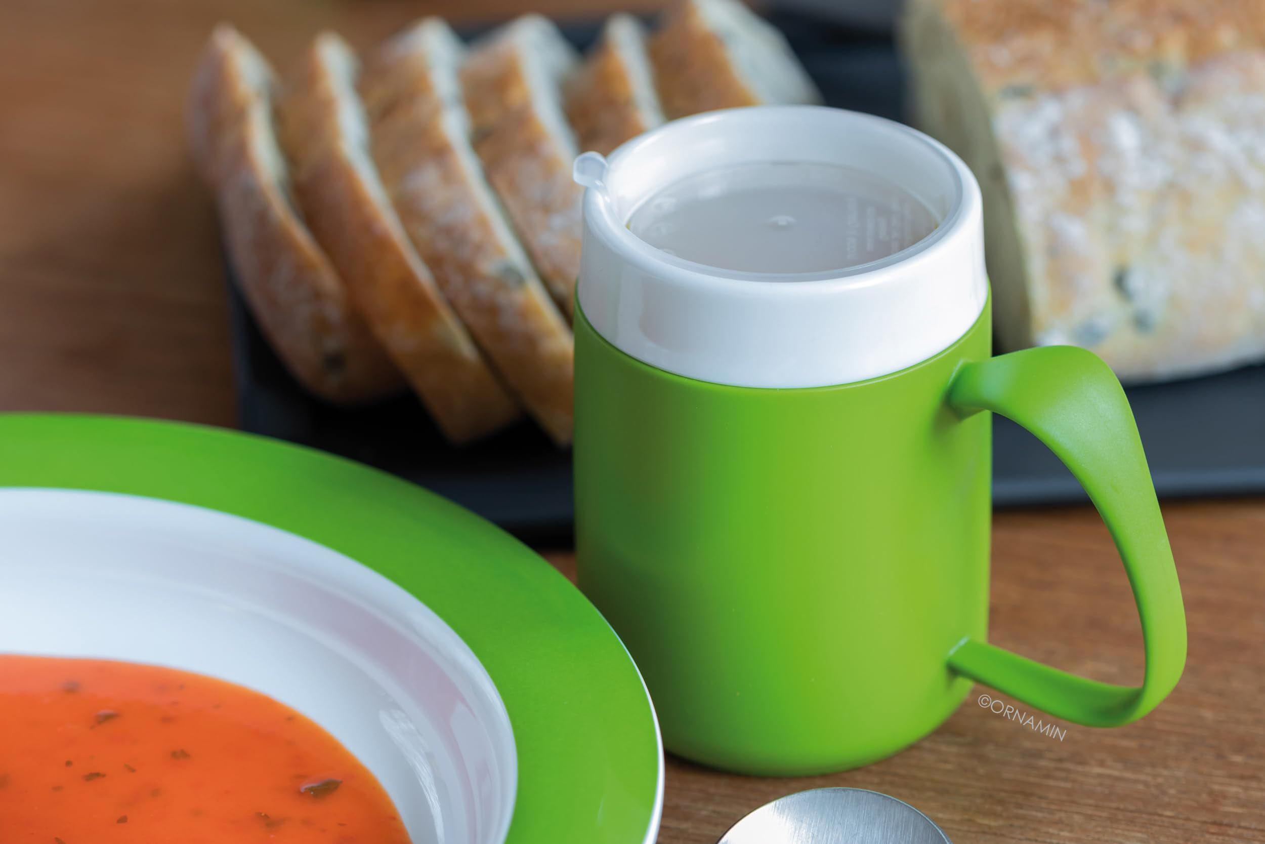Grüner Becher mit weißem Rand und Henkel, gefüllt mit Flüssigkeit.