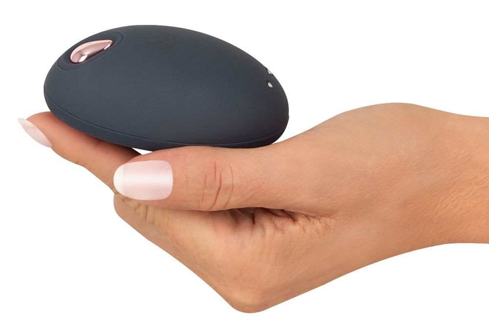Dunkelgrauer, ovaler Vibrator in einer Hand gehalten. Roségoldfarbener Akzent.