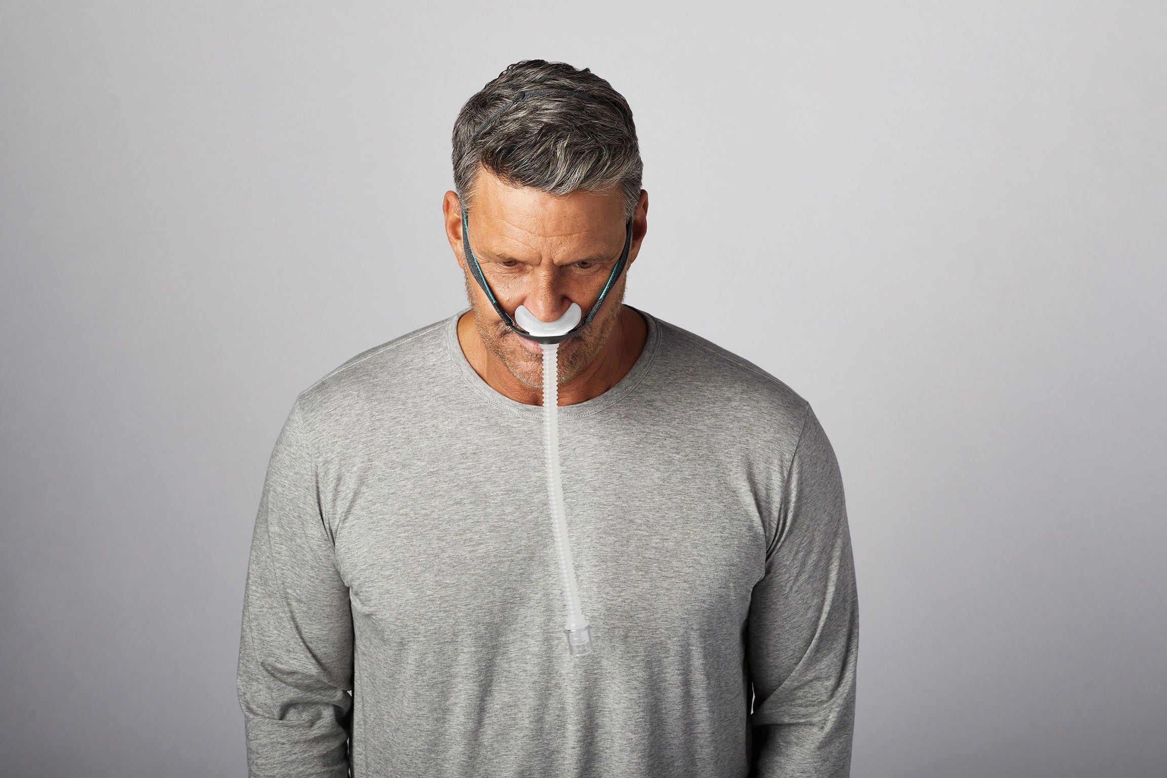 Mann trägt CPAP-Nasenmaske mit Schlauch.