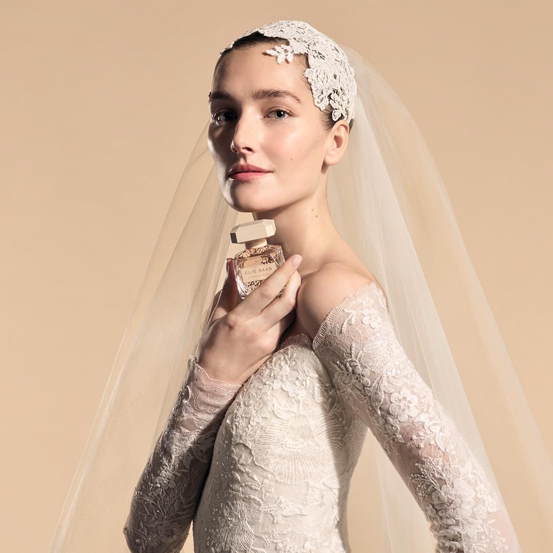 Braut hält Flakon. Aufschrift: Elie Saab Le Parfum Bridal. Brautkleid mit Spitze, Schleier.