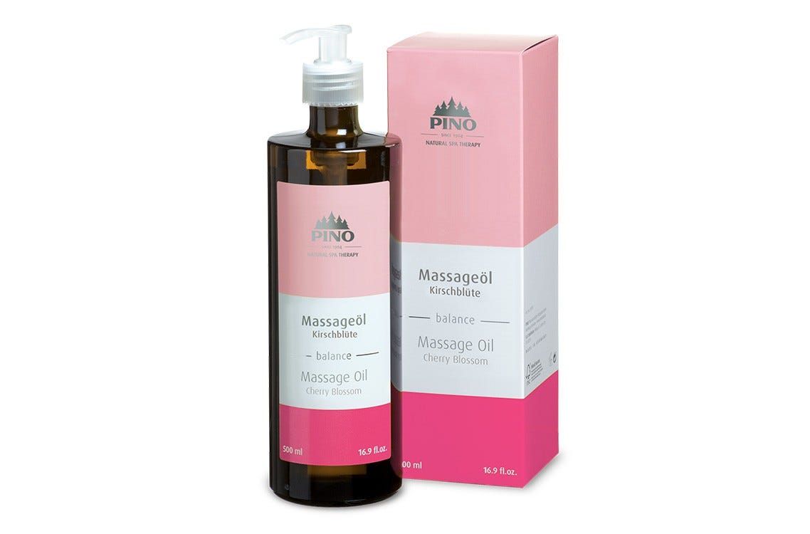 Braune Flasche mit Pumpe und rosa Etikett. Daneben eine rosa Schachtel. Auf beiden steht "Massageöl Kirschblüte".