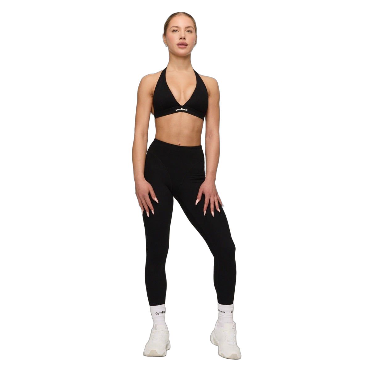 Frau in schwarzem Sport-BH mit Neckholder und Leggings, trägt weiße Socken.