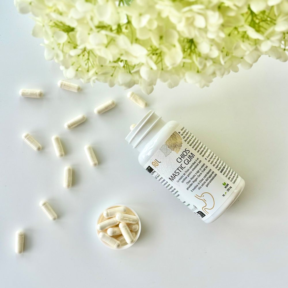Weiße Flasche mit Kapseln. Aufschrift: Chios Mastic Gum. Kapseln liegen verstreut und in einer kleinen Schale.